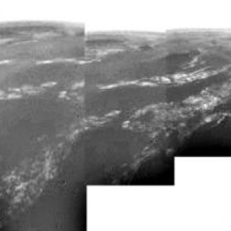 Panorama de 360° reconstitué avec les données de DISR lors de la descente de Huygens. La sonde était à 8 km d'altitude, et le cliché a une résolution de 20 m par pixel.

A gauche, on peut distinguer une frontière entre deux secteurs clairs et foncés. Les fines bandes claires pourraient être des bandes de brouillard. La sonde a dérivé au-dessus d'un "plateau" au centre et s'est dirigée vers son site d'atterrissage, secteur foncé à droite. La vitesse des vents a été estimée à environ 6 à 7 m/s.

© ES[...]