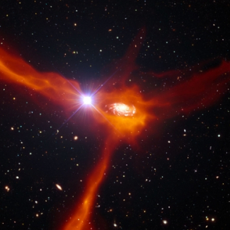Cette vue d'artiste montre une galaxie de l'Univers lointain, deux milliards d'années après le Big Bang, en train d'accréter le gaz froid environnant (en orange). Les astronomes ont été en mesure de collecter de nombreuses informations concernant cet objet en étendant leur étude à celle de la lumière émise par un quasar beaucoup plus distant (l'objet brillant situé à gauche de la galaxie centrale), dont l'alignement avec la galaxie d'avant-plan lui permet de briller au travers du gaz accrété. Les mouve[...]