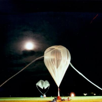 Instrument SPIRALE (LPC2E) sur le pas de lancement. La nacelle de 500 kg est suspendue juste au-dessus du sol par deux ballons auxiliaires (arrière plan) qui la maintiennent ainsi, le temps de déployer le ballon principal de 150 000 m<sup>3</sup>. Maintenu au sol, celui-ci est en cours de gonflage (premier plan). Une fois lâché, il entraînera la chaine de vol qui le relie à la nacelle. Les ballons auxiliaires se détacheront dès qu’elle sera tendue et retomberont au sol. © LPC2E[...]