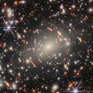 image du télescope James Webb, nombreuses étoiles et galaxies visibles, effet d'anneau de part et d'autre qui étire les images de certains objets