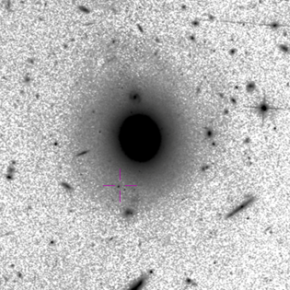 Image HST dans le domaine visible du champ de vue. La croix centrée sur un amas d'étoiles massif indique la position de la source, située à 12.5kpc d'une galaxie lenticulaire. Crédits : HST, Aladin@CDS[...]